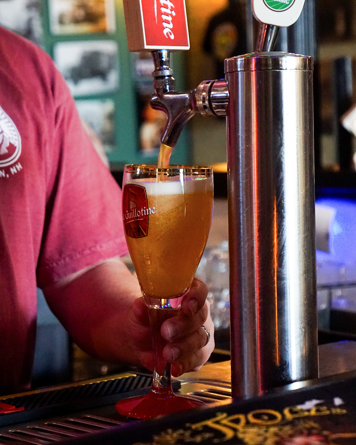 Barista pouring a beer into a goblet shaped glass from the tap.